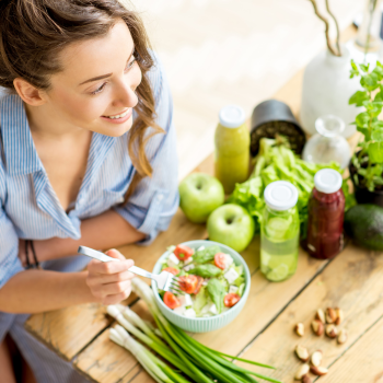 Junge Frau isst Salat und achtet auf die Ernährung bei Sodbrennen.
