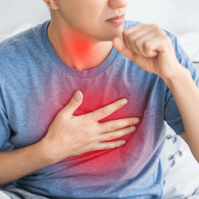 Mann hält sich die Hand auf die Brust und kämpft mit den Symptomen von Reflux.
